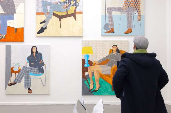 Eine Person steht vor einer Wand mit farbigen Protraitmalereien