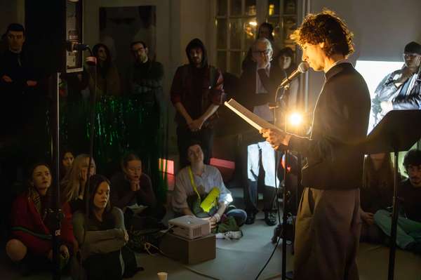 People sitting on the floor listening to someone reading aloud