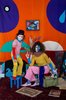 Die Fotografie zeigt ein Kind und eine erwachsene Person, in kunterbunten Farben in einem kunterbunten Raum. 