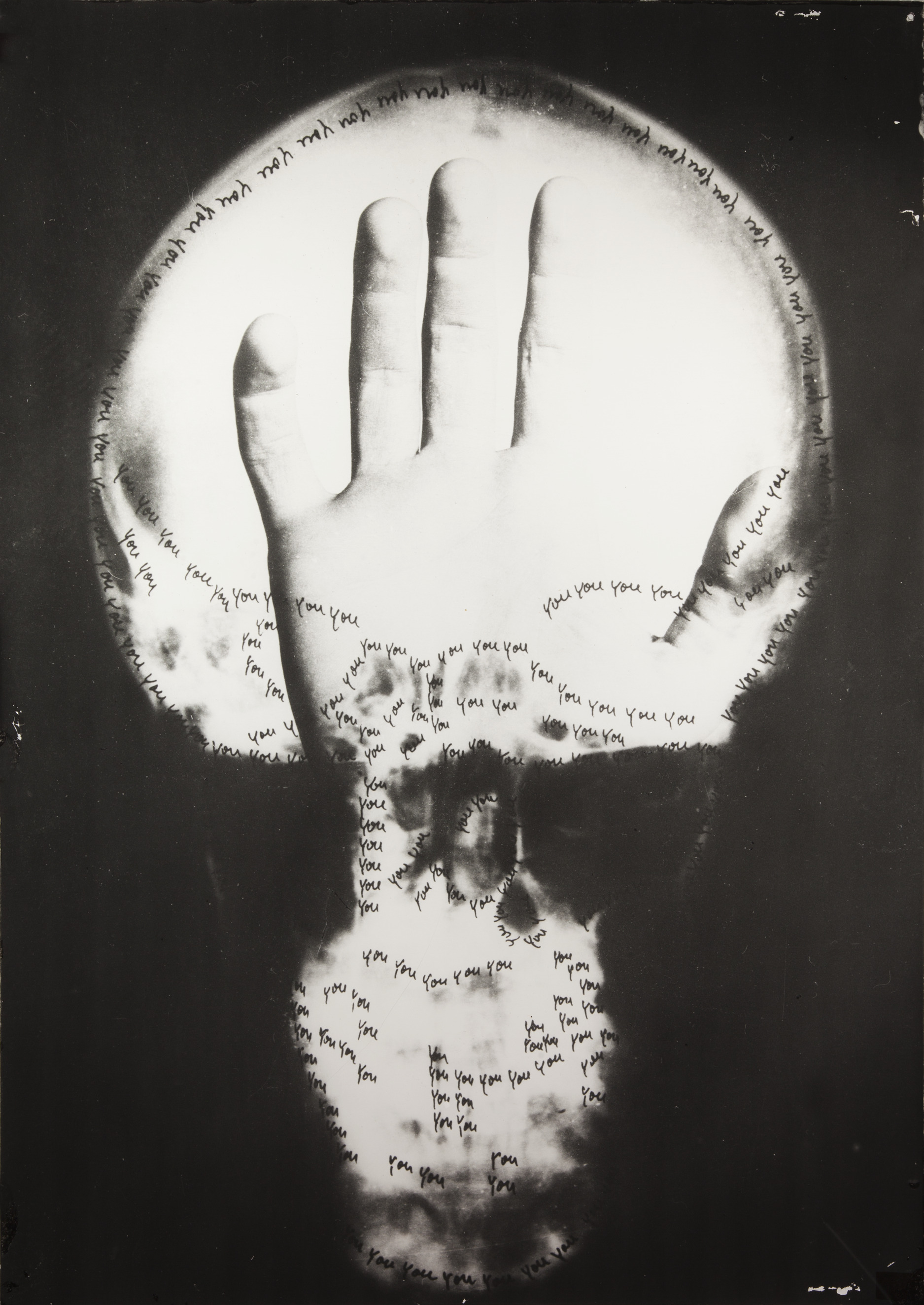 Black-and-white, surreal image showing an upright finger resembling an X-ray, transitioning into a human skull at the bottom; handwritten repetitions of the word “you” surround the finger and skull in circular and scattered patterns against a dark background.