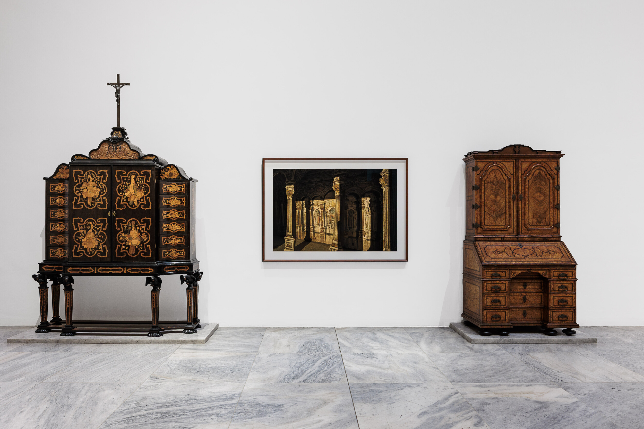 Zwischen Interieurs aus Barock, Rokoko und Klassizismus hängt eine Schwarz-gerahmte Fotografie.