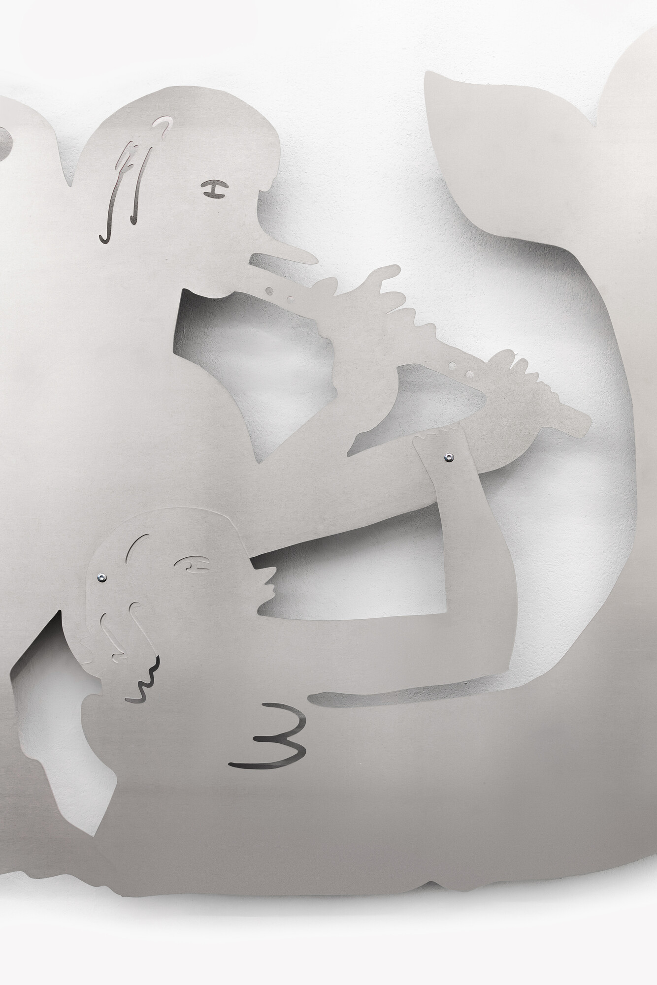 Abstrakte, ausgeschnittene Metallformen an einer Wand, die stilisierte Figuren zeigen, die sich gegenüberliegen und ein längliches Objekt zwischen sich halten.