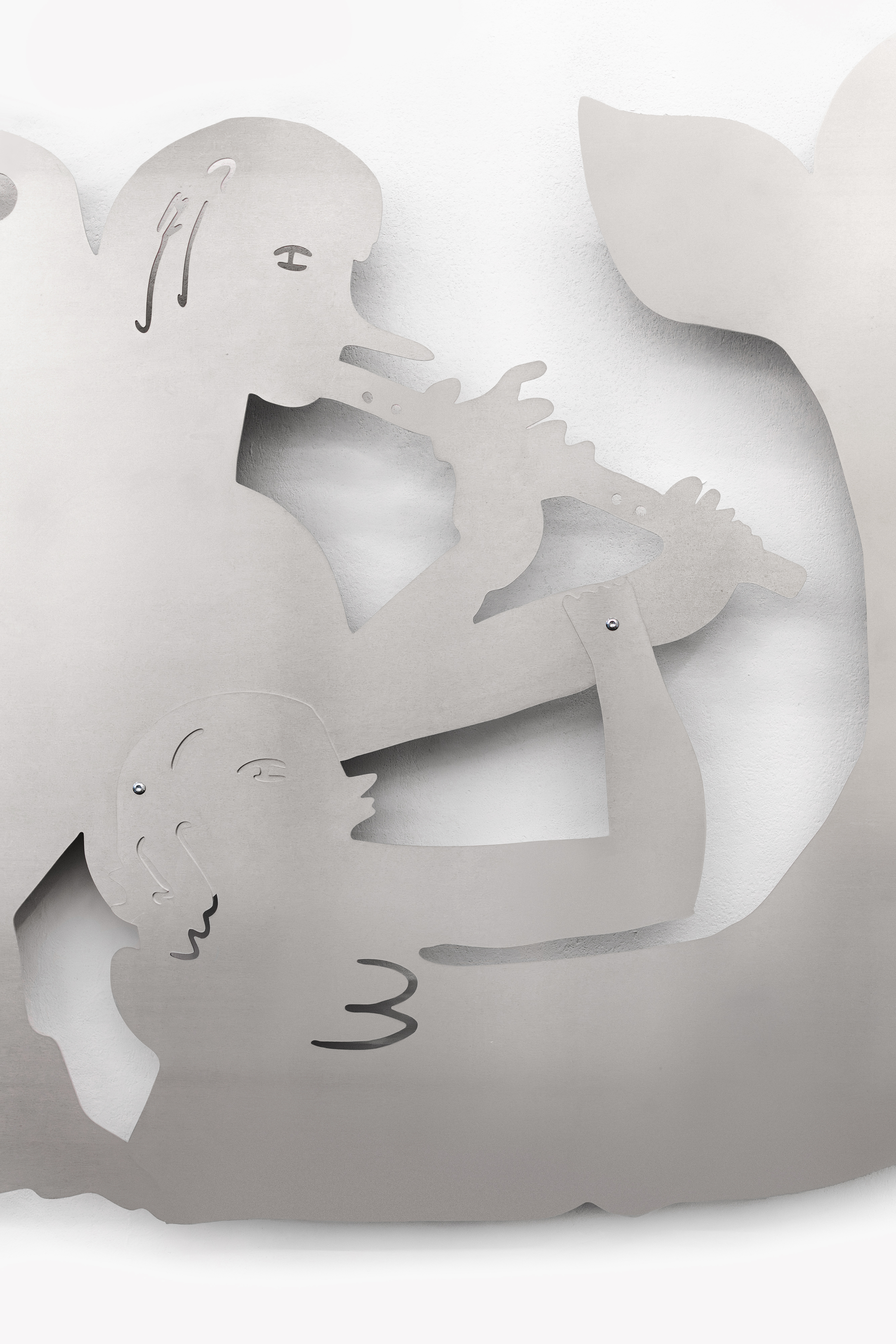 Abstrakte, ausgeschnittene Metallformen an einer Wand, die stilisierte Figuren zeigen, die sich gegenüberliegen und ein längliches Objekt zwischen sich halten.