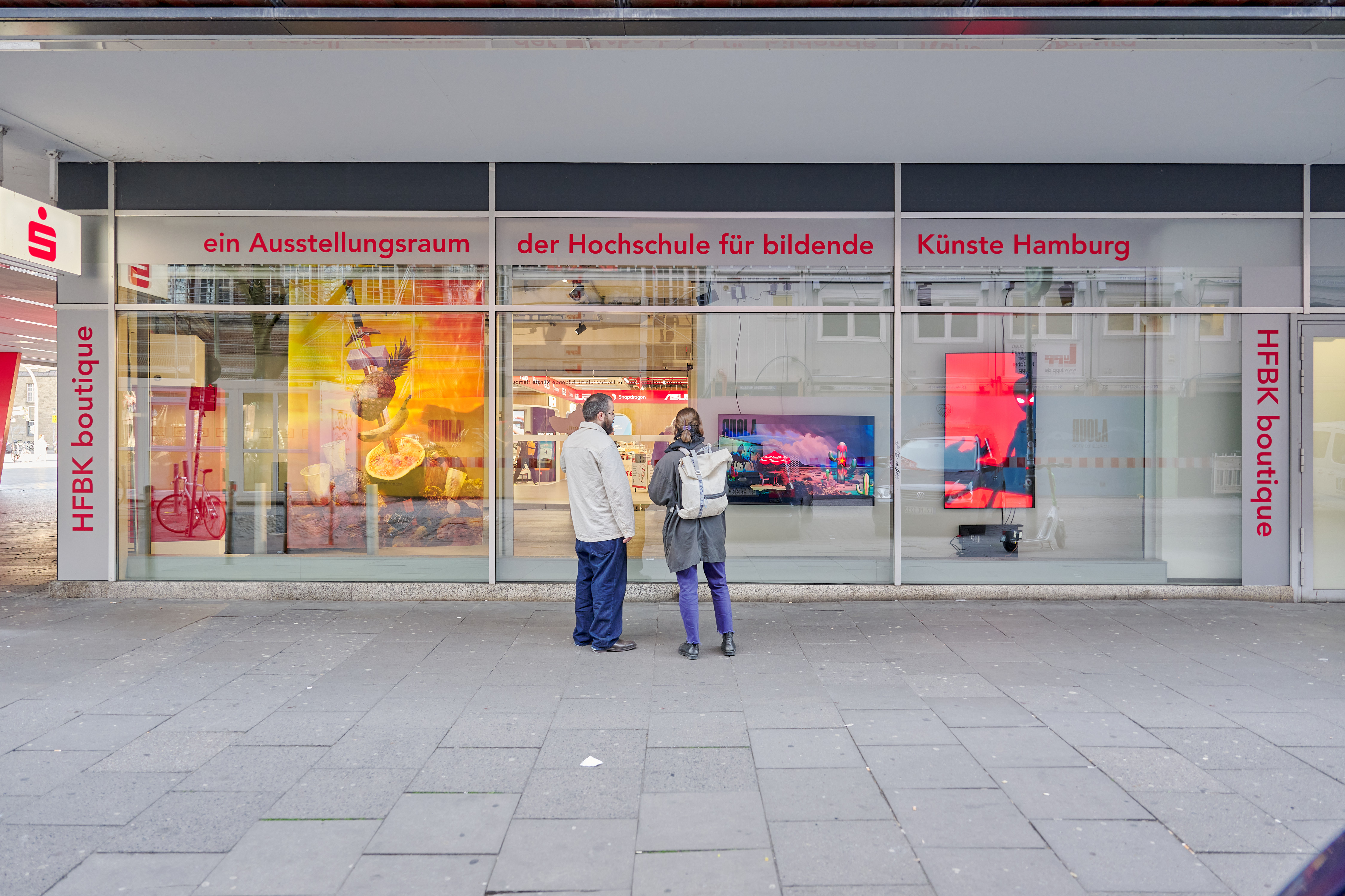 Two people are standing in front of a shop window.