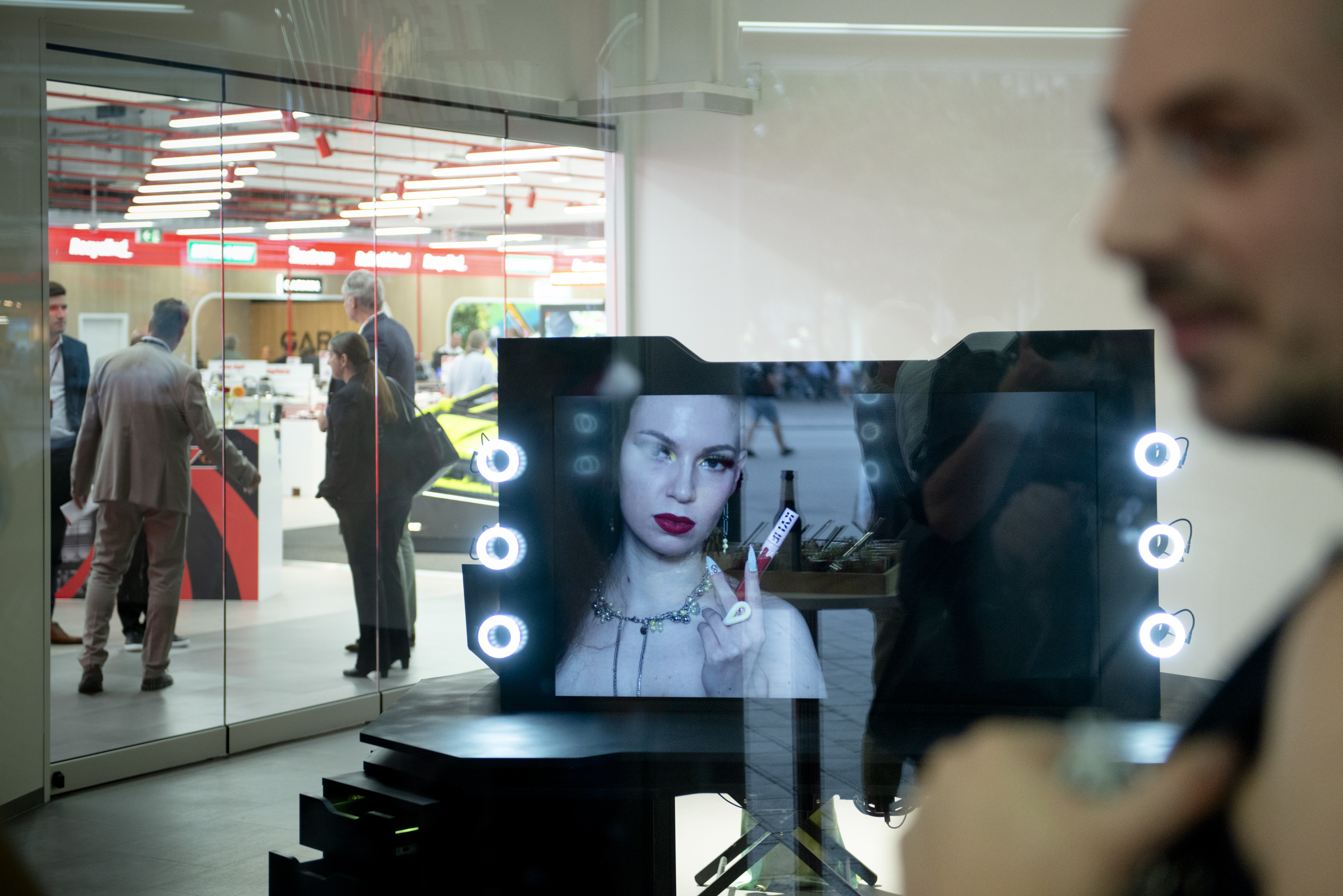 The face of a woman can be seen in a mirror on a dressing table in a department store