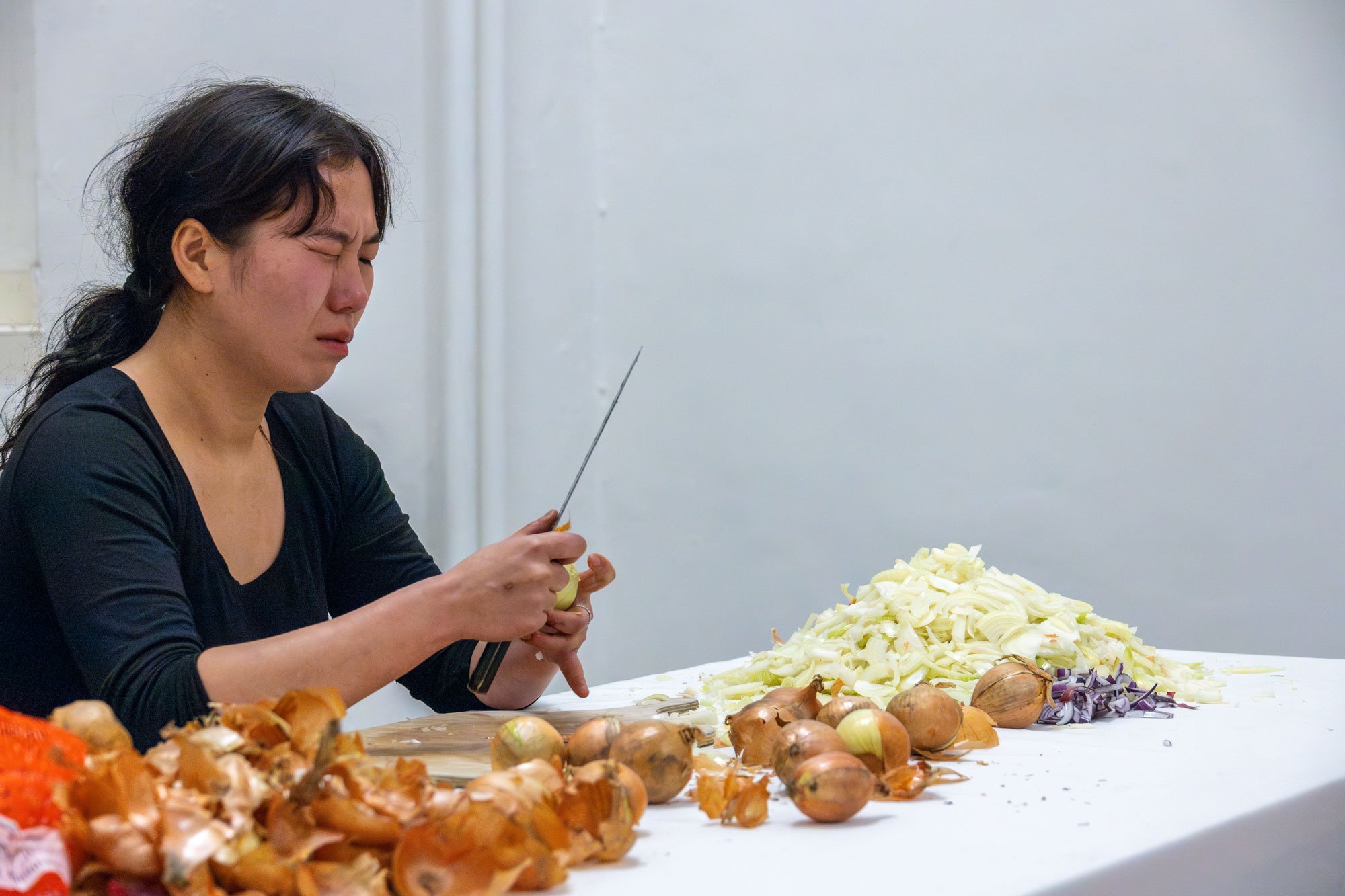 A woman peels onions.