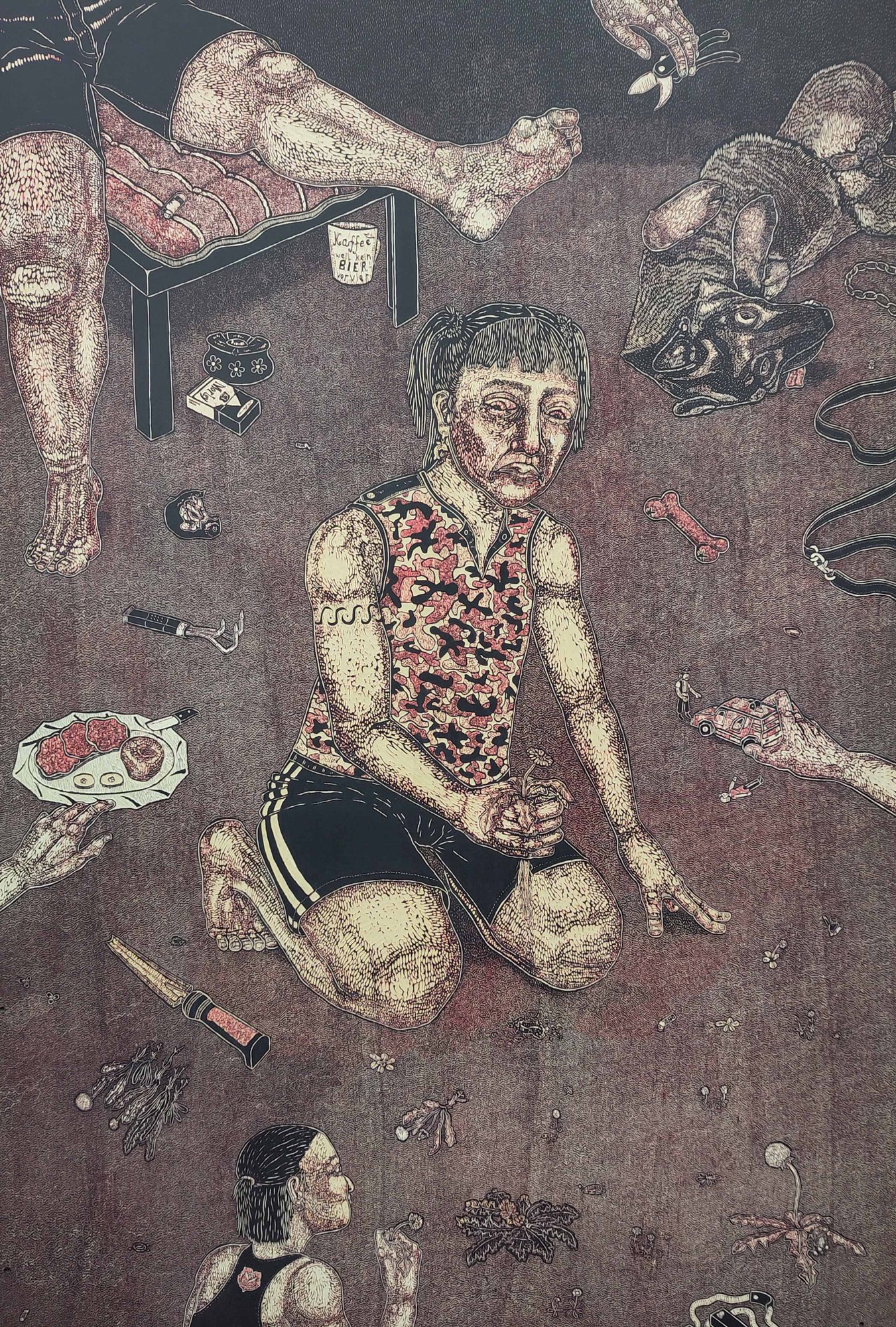 A figure wearing shorts kneels on the floor, surrounded by scattered objects and framed by the body parts of other figures protruding into the picture against a dark background.