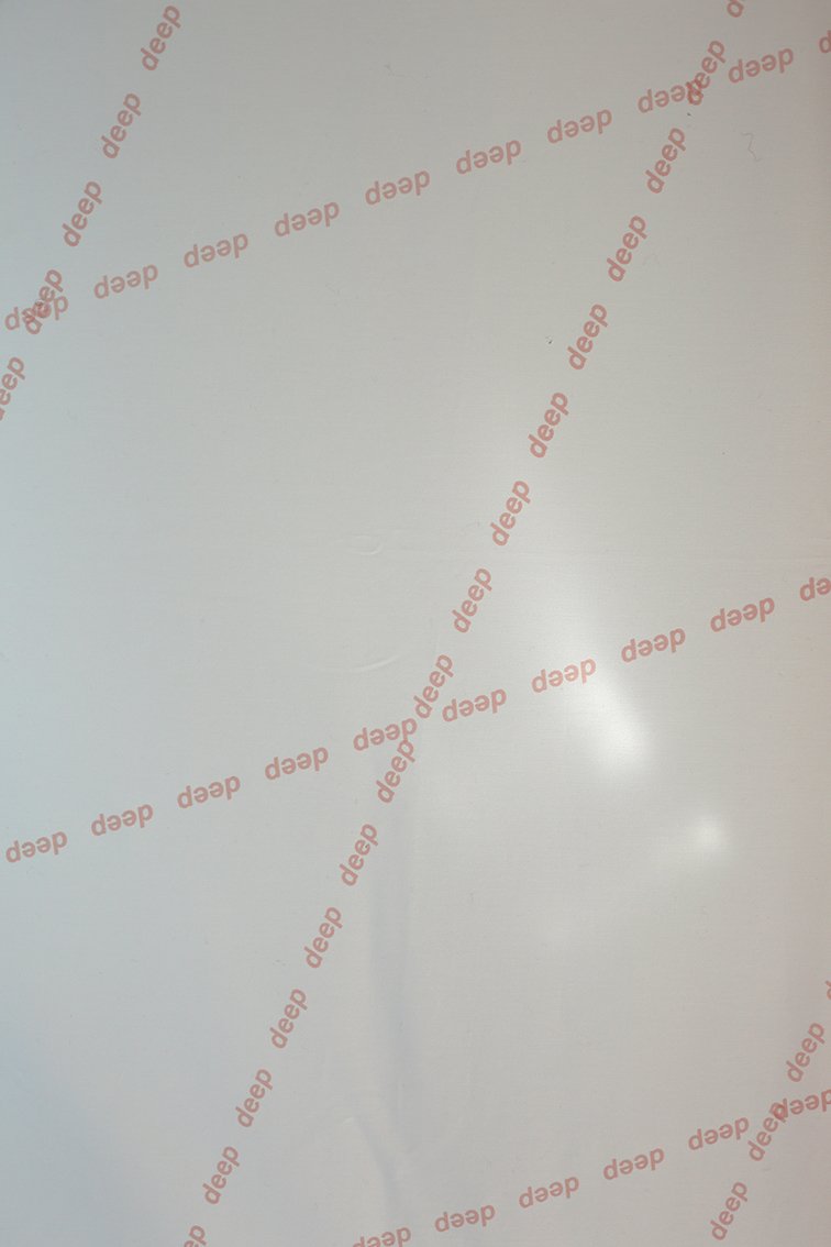 The word “deep” appears repeatedly in small red type, diagonally arranged on a smooth white surface.