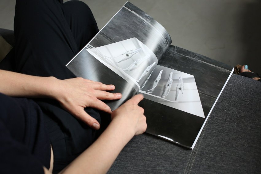A person’s hands turning pages of a magazine featuring a photograph of white technical object installations.