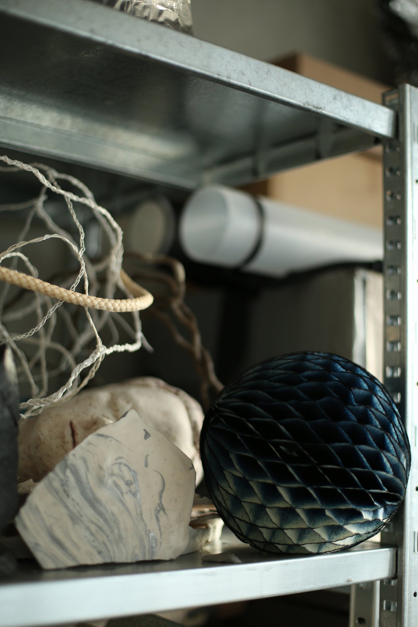 Metal shelf holding various materials, including a dark honeycomb-like object, pale stones, and wire-like structures.
