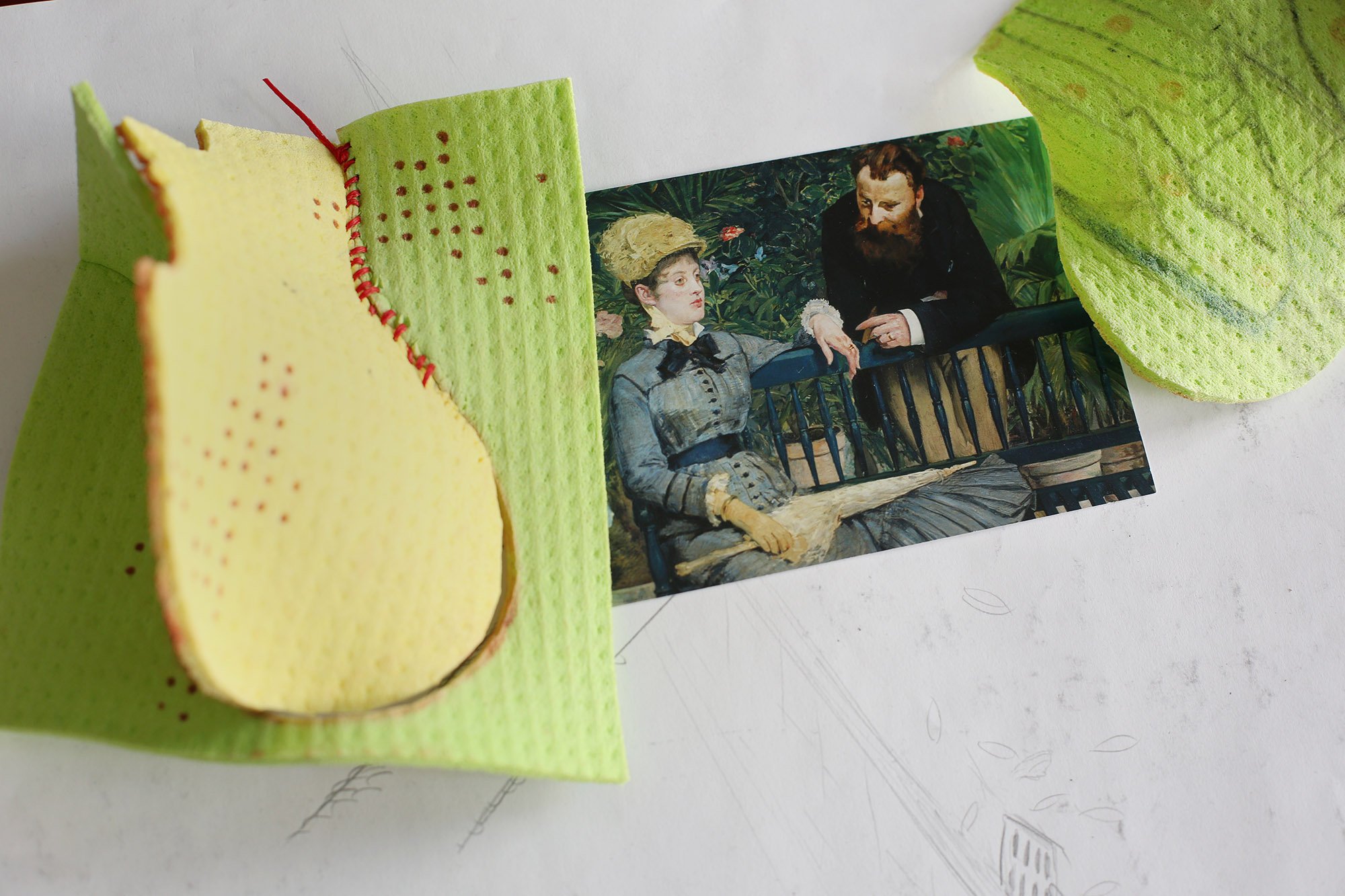 Close-up of a yellow-green textured piece with red stitching beside a postcard of a historical painting showing a woman and a man on a bench.