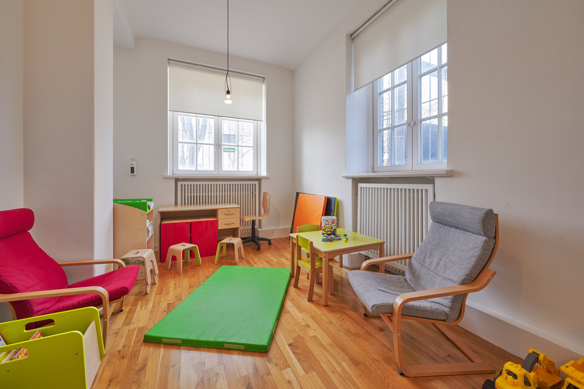 View of a room with colorful, comfortable armchairs, toys, and children's furniture