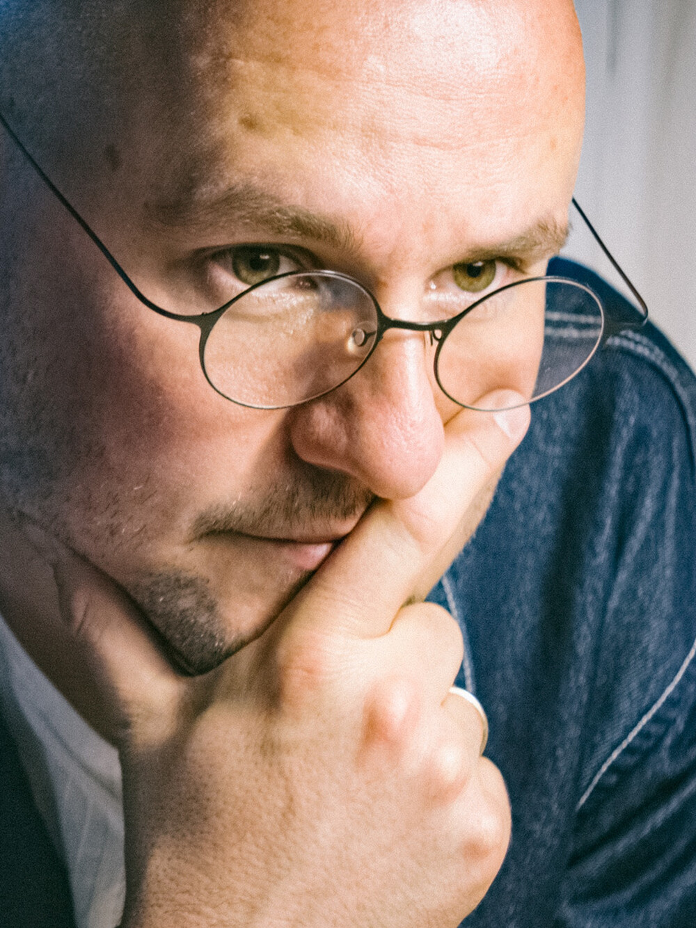 Porträt eines Mannes mit Brille, der Kopf leicht angeschnitten am oberen Bildrand.