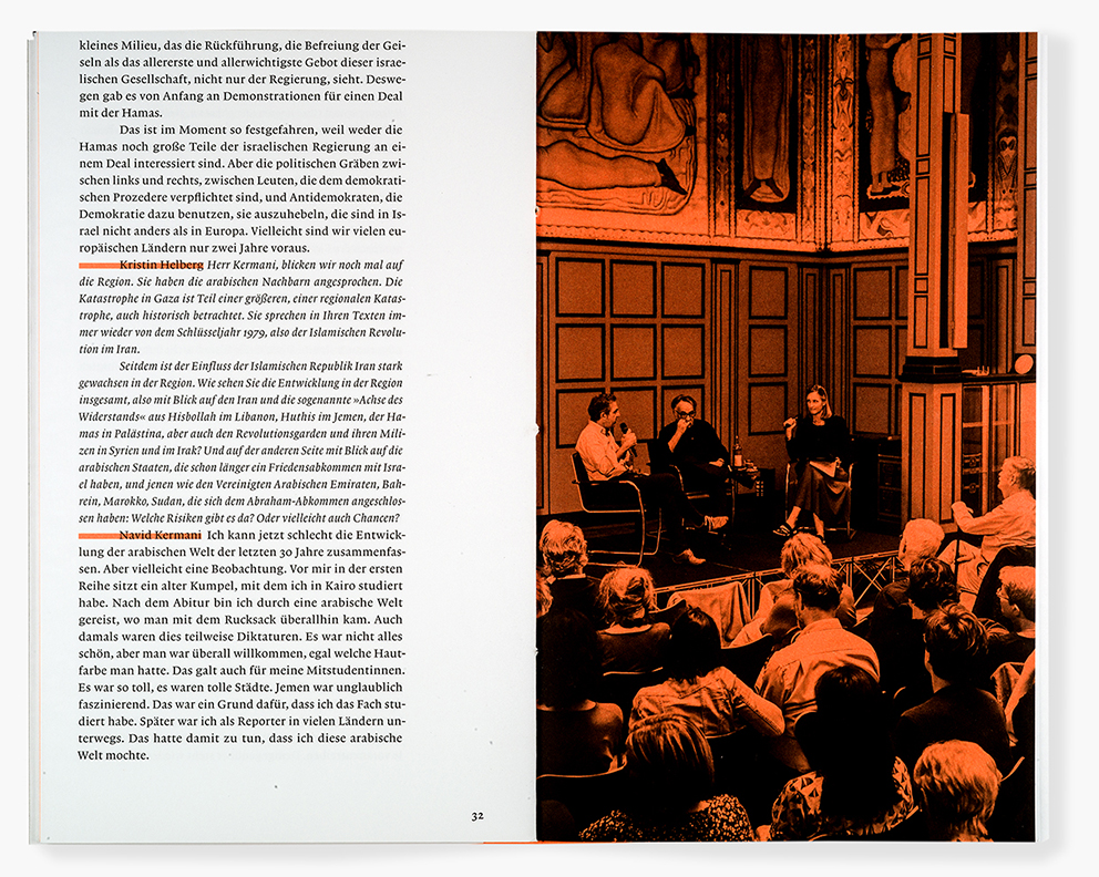 Doppelseite eines Buches: Links eine Seite mit fortlaufendem deutschsprachigem Interviewtext, einzelne Namen wie „Kristin Helberg“ und „Navid Kermani“ sind hervorgehoben. Rechts eine ganzseitige, orange eingefärbte Fotografie einer Podiumsdiskussion in einem historischen Saal mit Wandvertäfelung und Wandmalereien. Drei Personen sitzen vorne auf einer Bühne mit Mikrofonen, davor ein dicht besetztes Publikum, das aufmerksam zuhört.