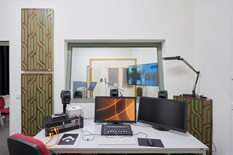 Computer auf einem Schreibtisch vor einem Fenster zu einem anderen Raum