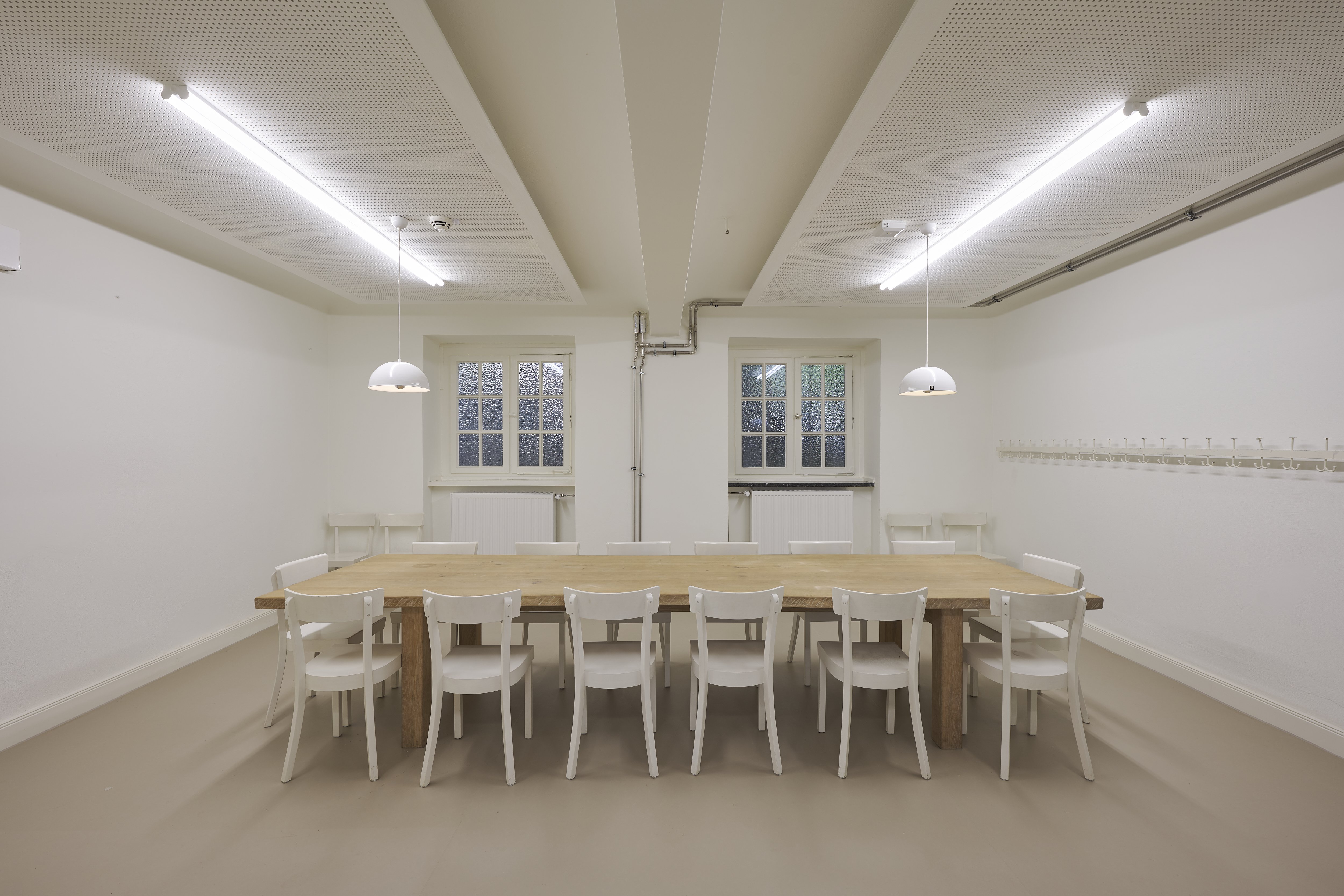 Ein Holztisch mit 12 Stühlen in einem kleinen Raum