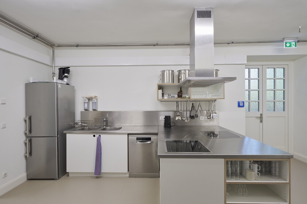 Eine Küchenzeile mit Kühlschrank, Spüle, Herd und Abzugshaube.