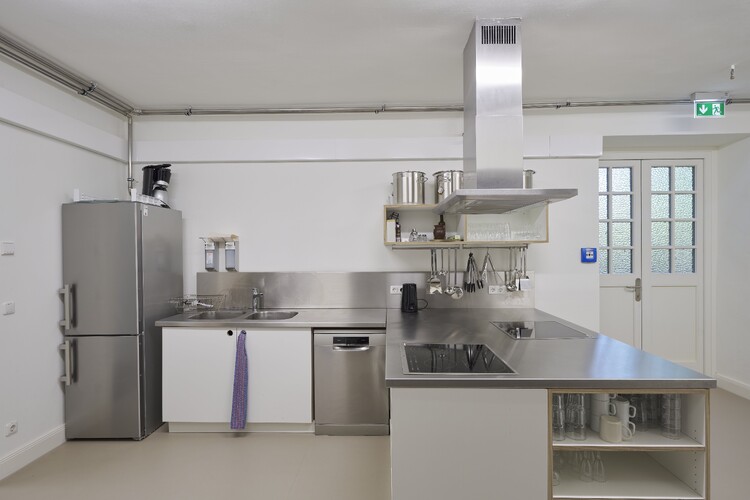 Eine Küchenzeile mit Kühlschrank, Spüle, Herd und Abzugshaube.