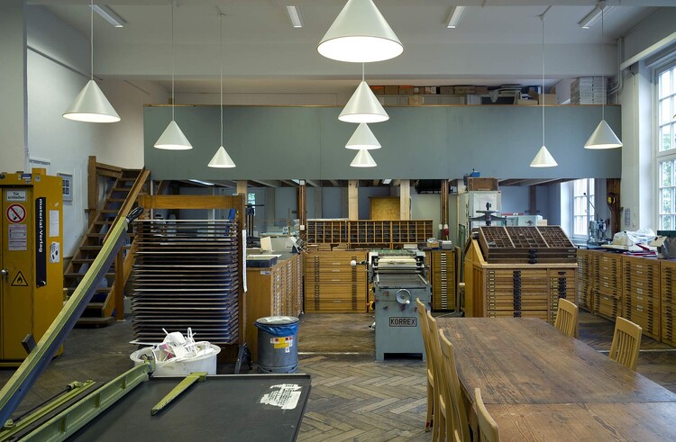 Schneidemaschine, Setzkästen mit Buchdrucklettern, ein Arbeitstisch mit Stühlen.