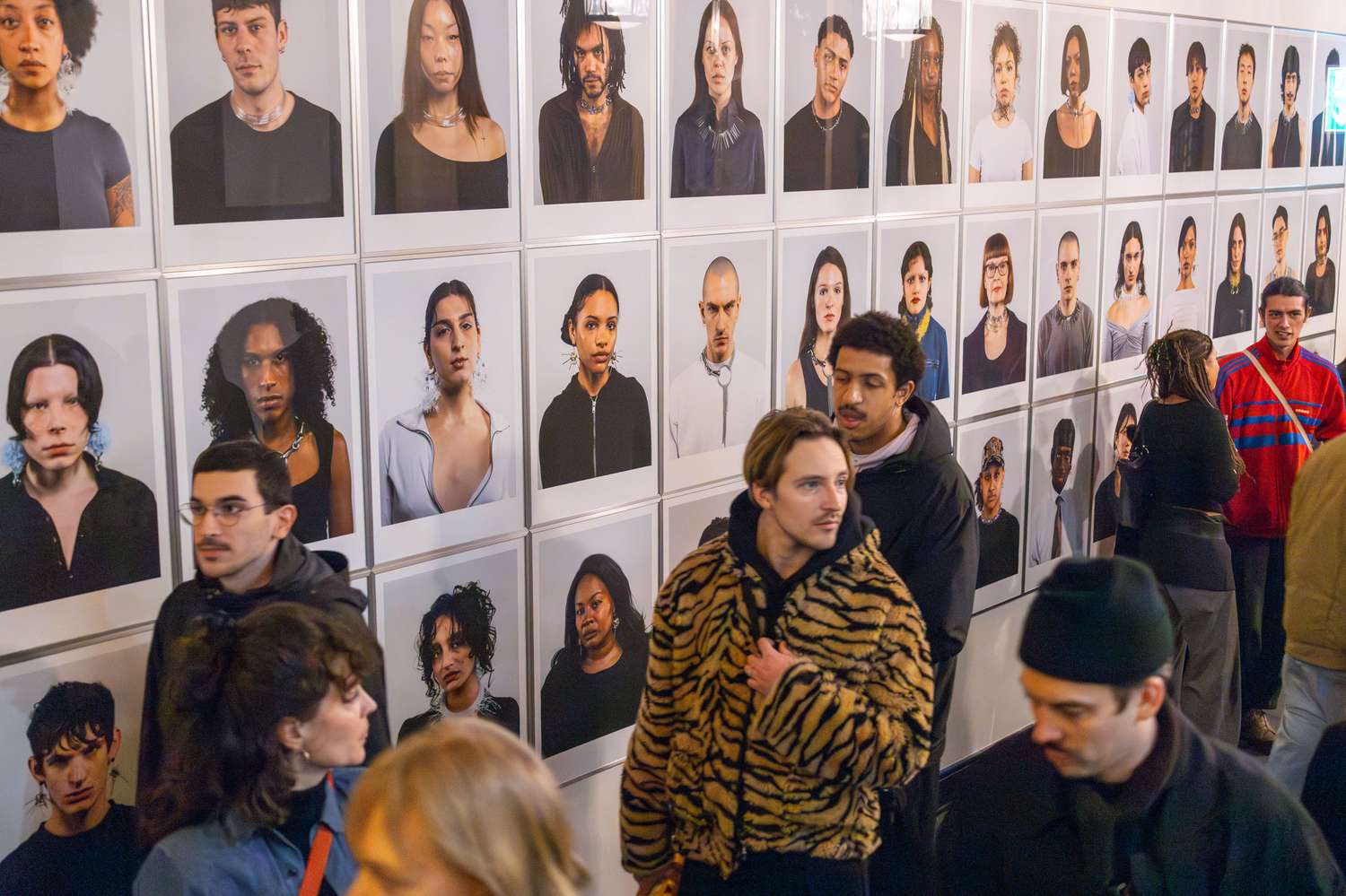 Viele Menschen stehen vor einer Wand mit Portrait-Fotografien
