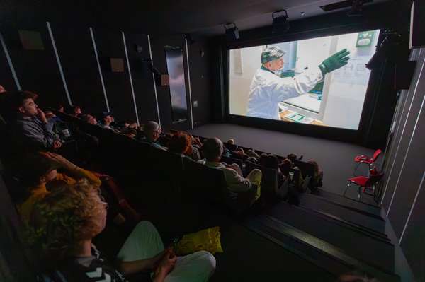 Eine dunkler kleiner Kinosaal mit vollbesetzten Besucherraum. Auf der Leinwand läuft ein Film.